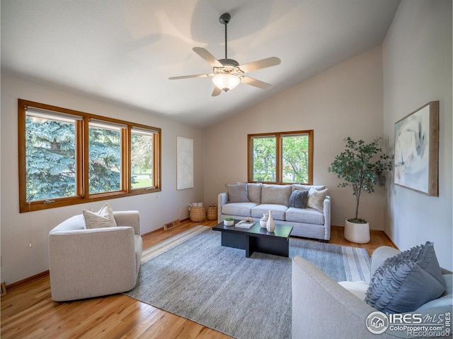 living area featuring a ceiling fan, lofted ceiling, light wood finished floors, and baseboards