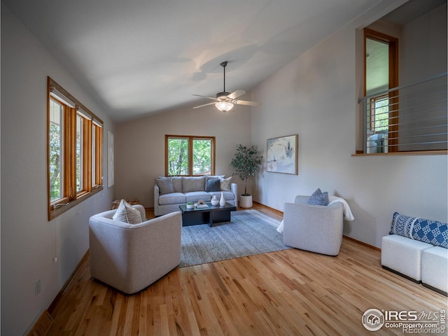 living area with wood finished floors, lofted ceiling, baseboards, and a ceiling fan