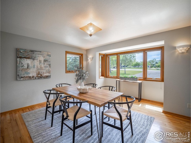 dining area with baseboards and light wood-style flooring