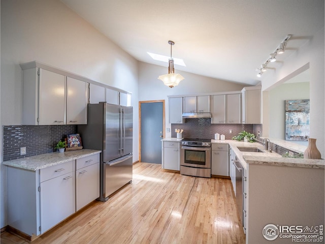 kitchen featuring appliances with stainless steel finishes, a sink, lofted ceiling, tasteful backsplash, and a skylight