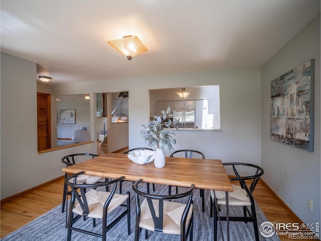 dining space with wood finished floors, baseboards, and stairs