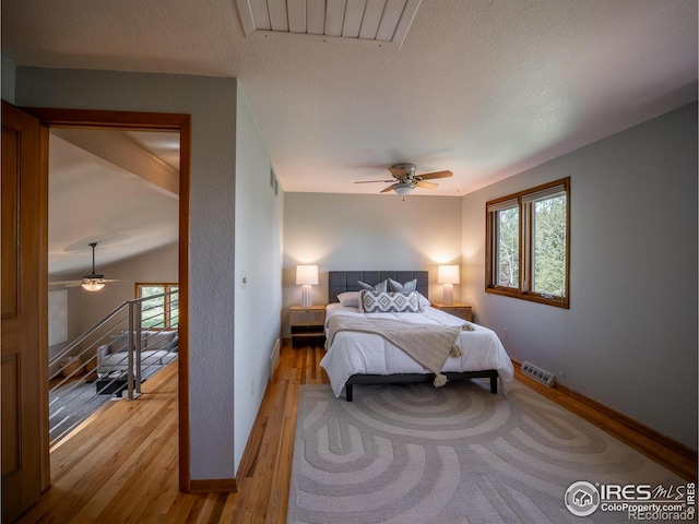 bedroom featuring light wood-style floors, baseboards, a ceiling fan, and a textured ceiling