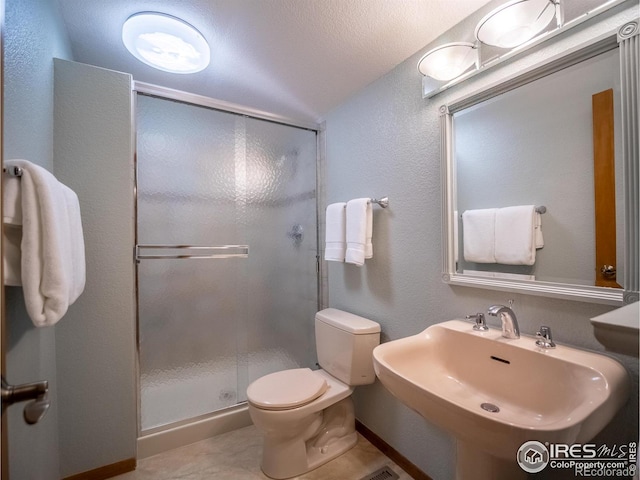 bathroom featuring a shower stall, toilet, a sink, lofted ceiling, and a textured wall