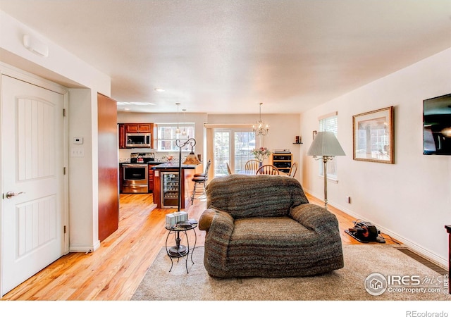 11656 Logan St, Northglenn, CO 80233 - living room with beverage cooler, a chandelier, light wood-type flooring, and baseboards