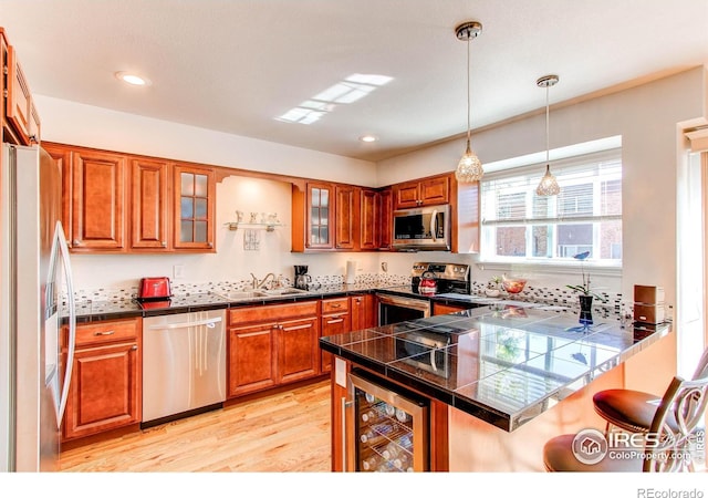 11656 Logan St, Northglenn, CO 80233 - kitchen with stainless steel appliances, a peninsula, a kitchen bar, beverage cooler, and brown cabinetry