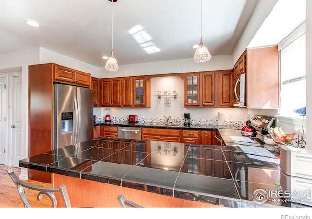 11656 Logan St, Northglenn, CO 80233 - kitchen featuring appliances with stainless steel finishes, brown cabinets, tile countertops, a peninsula, and recessed lighting