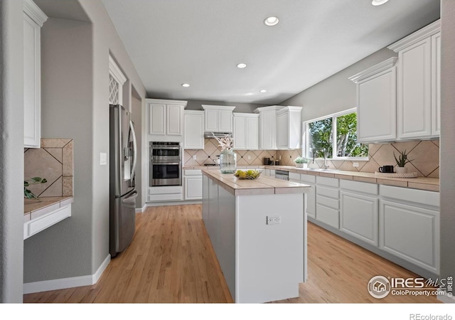 2458 Vale Way, Erie, CO 80516 - kitchen with stainless steel appliances, tile counters, a kitchen island, white cabinetry, and recessed lighting