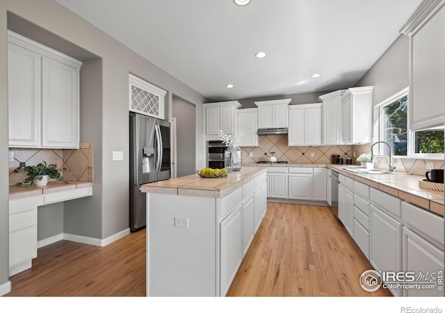 2458 Vale Way, Erie, CO 80516 - kitchen with appliances with stainless steel finishes, a center island, white cabinetry, decorative backsplash, and recessed lighting
