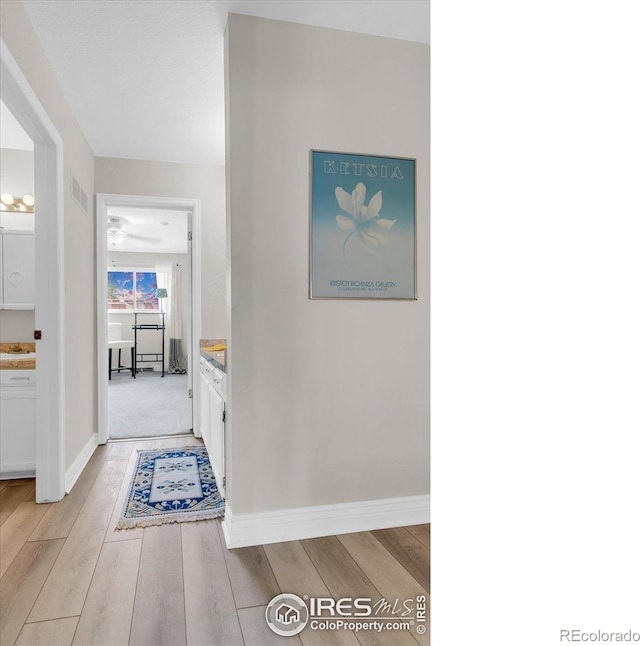 hallway with light wood finished floors and baseboards