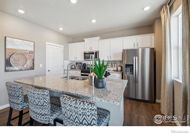 kitchen with appliances with stainless steel finishes, a sink, dark wood-style flooring, white cabinetry, and recessed lighting