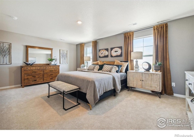 bedroom with light colored carpet and baseboards