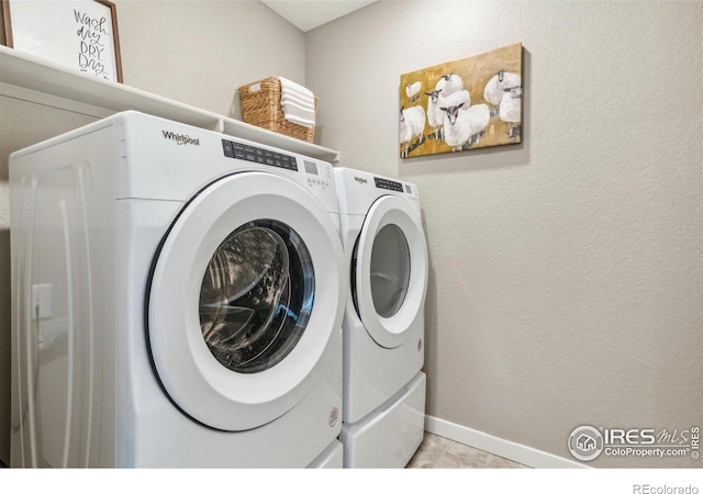 laundry room featuring washer and dryer, baseboards, and light tile patterned floors