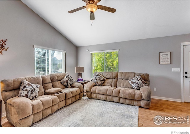 living area with light wood-type flooring, ceiling fan, baseboards, and high vaulted ceiling