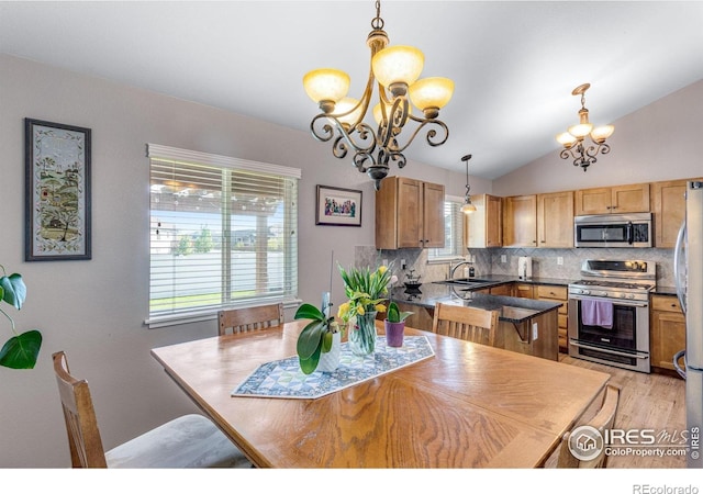 dining area with a chandelier, light wood-style flooring, and vaulted ceiling