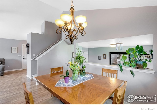 dining room with a chandelier, light wood-style flooring, stairs, and baseboards