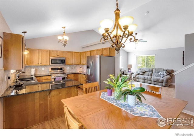 kitchen with stainless steel appliances, a sink, a chandelier, lofted ceiling, and a peninsula
