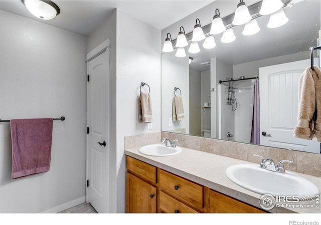 full bath featuring curtained shower, double vanity, and baseboards