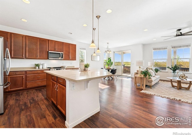 kitchen with stainless steel appliances, plenty of natural light, dark wood-style flooring, recessed lighting, and a kitchen island