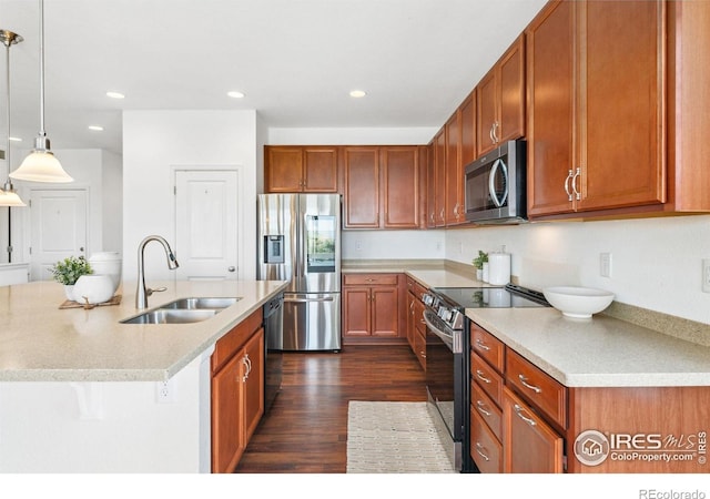 kitchen featuring appliances with stainless steel finishes, a sink, dark wood-style flooring, light countertops, and hanging light fixtures