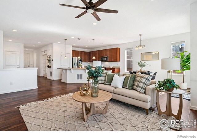 living area with dark wood finished floors, a ceiling fan, recessed lighting, and baseboards