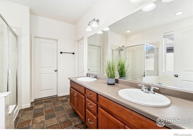 bathroom featuring a stall shower, double vanity, baseboards, and stone finish flooring