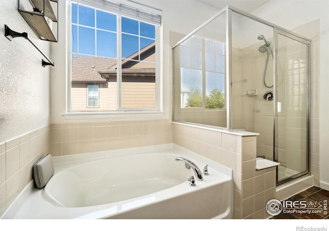 bathroom with a shower stall, plenty of natural light, and a garden tub
