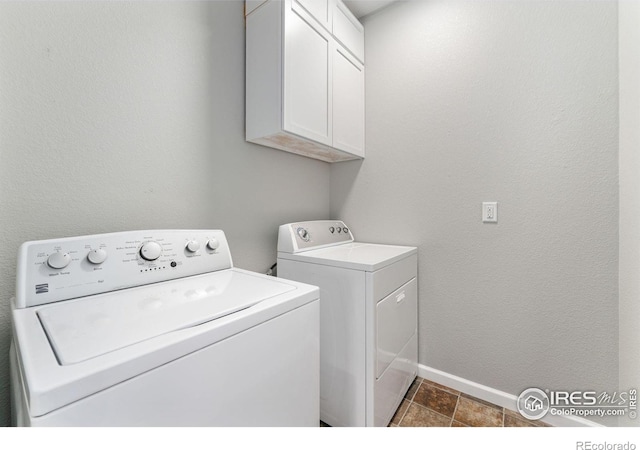 clothes washing area with cabinet space, washing machine and dryer, and baseboards