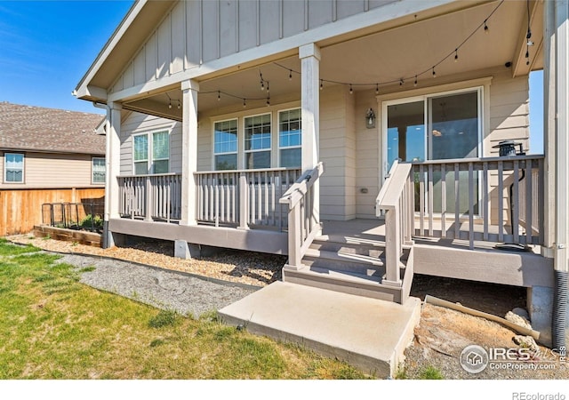 view of exterior entry with board and batten siding and fence