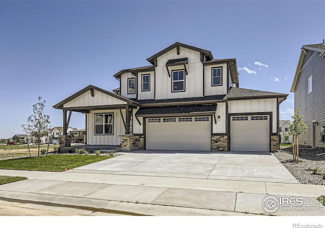 1679 Crystalline Dr, Windsor, CO 80550 - view of front of home featuring board and batten siding, covered porch, driveway, an attached garage, and stone siding
