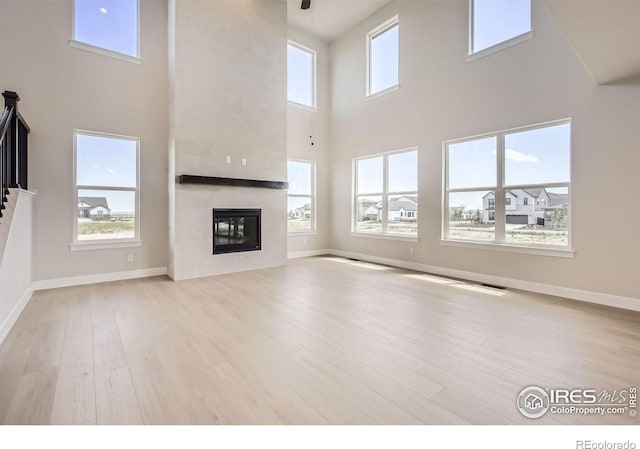 1679 Crystalline Dr, Windsor, CO 80550 - unfurnished living room with a high ceiling, wood finished floors, a fireplace, and baseboards
