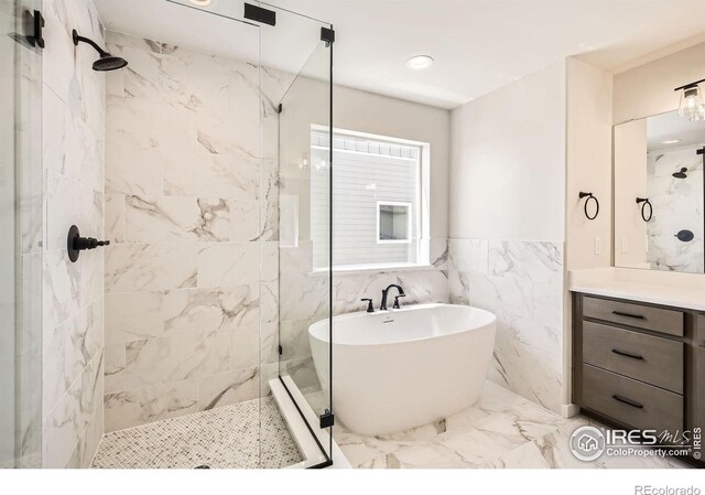 1679 Crystalline Dr, Windsor, CO 80550 - bathroom with a tile shower, a soaking tub, marble finish flooring, vanity, and tile walls