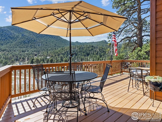 658 Cedar Ridge Cir, Estes Park, CO 80517 - wooden terrace featuring a wooded view, outdoor dining space, and a mountain view