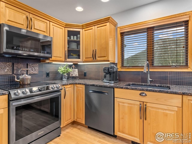 658 Cedar Ridge Cir, Estes Park, CO 80517 - kitchen featuring appliances with stainless steel finishes, a sink, light wood-style flooring, glass insert cabinets, and tasteful backsplash