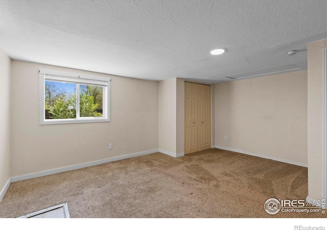 empty room with carpet flooring, a textured ceiling, and baseboards