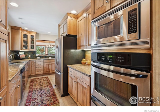 1433 Vista View Ln, Estes Park, CO 80517 - kitchen with appliances with stainless steel finishes, light stone counters, backsplash, glass insert cabinets, and a sink