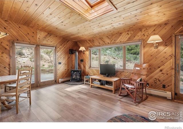 1433 Vista View Ln, Estes Park, CO 80517 - living area featuring a baseboard heating unit, a wood stove, wooden walls, a baseboard radiator, and light wood-type flooring