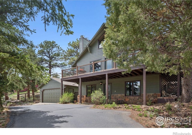 1433 Vista View Ln, Estes Park, CO 80517 - view of front of home featuring stone siding, a detached garage, a wooden deck, a chimney, and an outbuilding