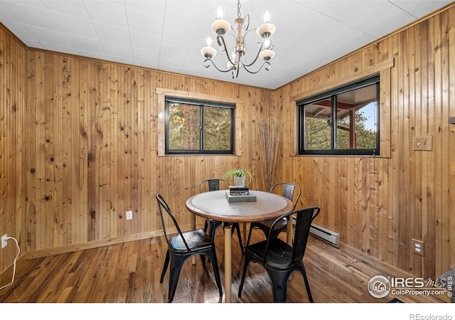 31 Cedar Dr, Lyons, CO 80540 - dining space with a chandelier, wood-type flooring, baseboards, wooden walls, and a baseboard heating unit