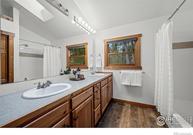 31 Cedar Dr, Lyons, CO 80540 - bathroom with wood finished floors, lofted ceiling, a skylight, double vanity, and baseboards
