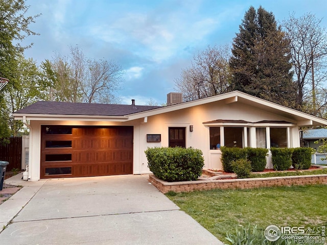 view of front facade featuring driveway, an attached garage, and fence