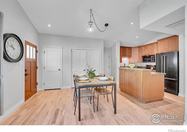 kitchen featuring appliances with stainless steel finishes, vaulted ceiling, light countertops, light wood-type flooring, and baseboards