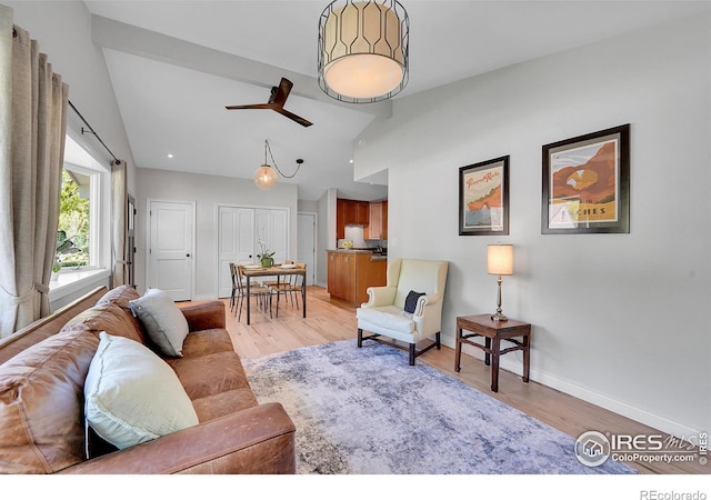 living area featuring light wood finished floors, baseboards, a ceiling fan, and high vaulted ceiling