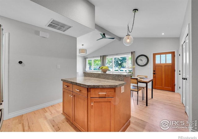 kitchen with light wood-type flooring, vaulted ceiling, decorative light fixtures, brown cabinets, and tile countertops