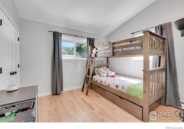 bedroom with lofted ceiling, wood finished floors, and baseboards
