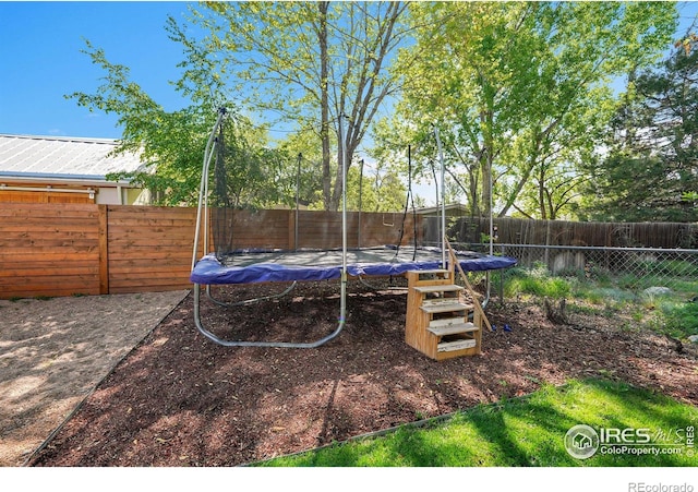fenced backyard featuring a trampoline