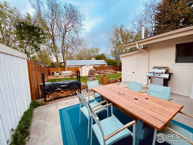 view of patio featuring outdoor dining space, a storage shed, an outdoor structure, and a fenced backyard