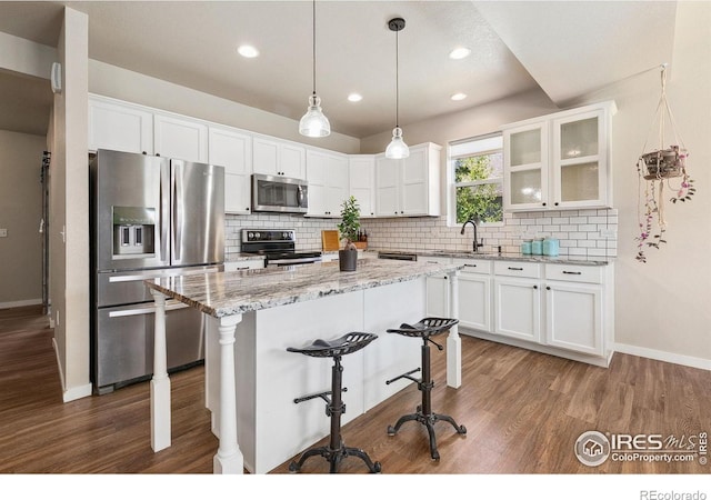kitchen with appliances with stainless steel finishes, baseboards, a breakfast bar, dark wood-style flooring, and recessed lighting