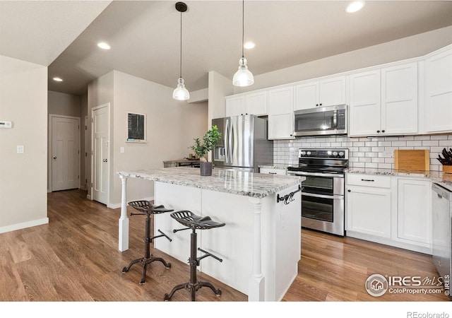 kitchen featuring appliances with stainless steel finishes, decorative backsplash, a kitchen island, white cabinetry, and recessed lighting
