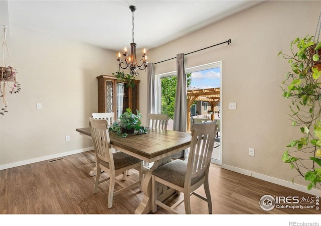 dining space with a chandelier, wood finished floors, and baseboards