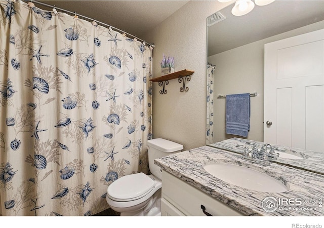bathroom featuring a textured wall, toilet, vanity, and curtained shower